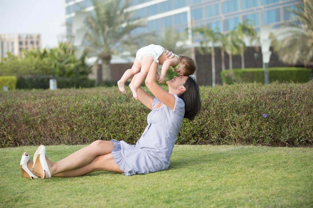 a mother and baby playing on a grassy field