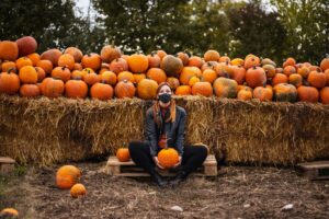 woman sitting crossed legged and posing in front of pumpkins