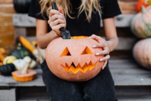 a woman holding a carved pumpkin