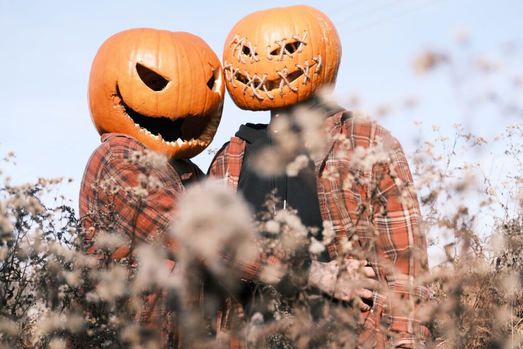 couple in pumpkin heads on meadow