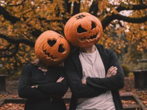 couple with pumpkin heads in autumn park