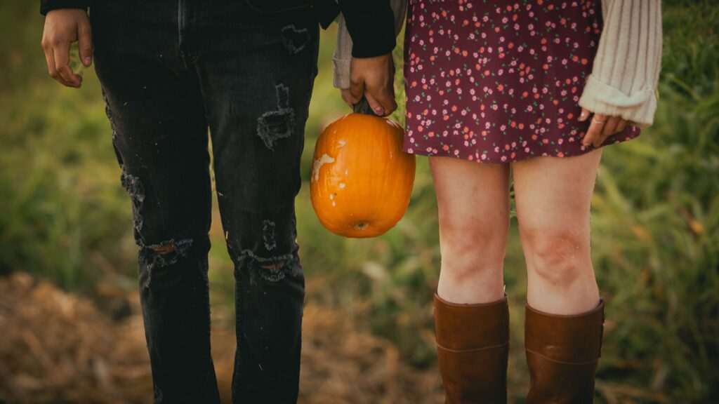 young couple holding a pumpkin in autumn setting